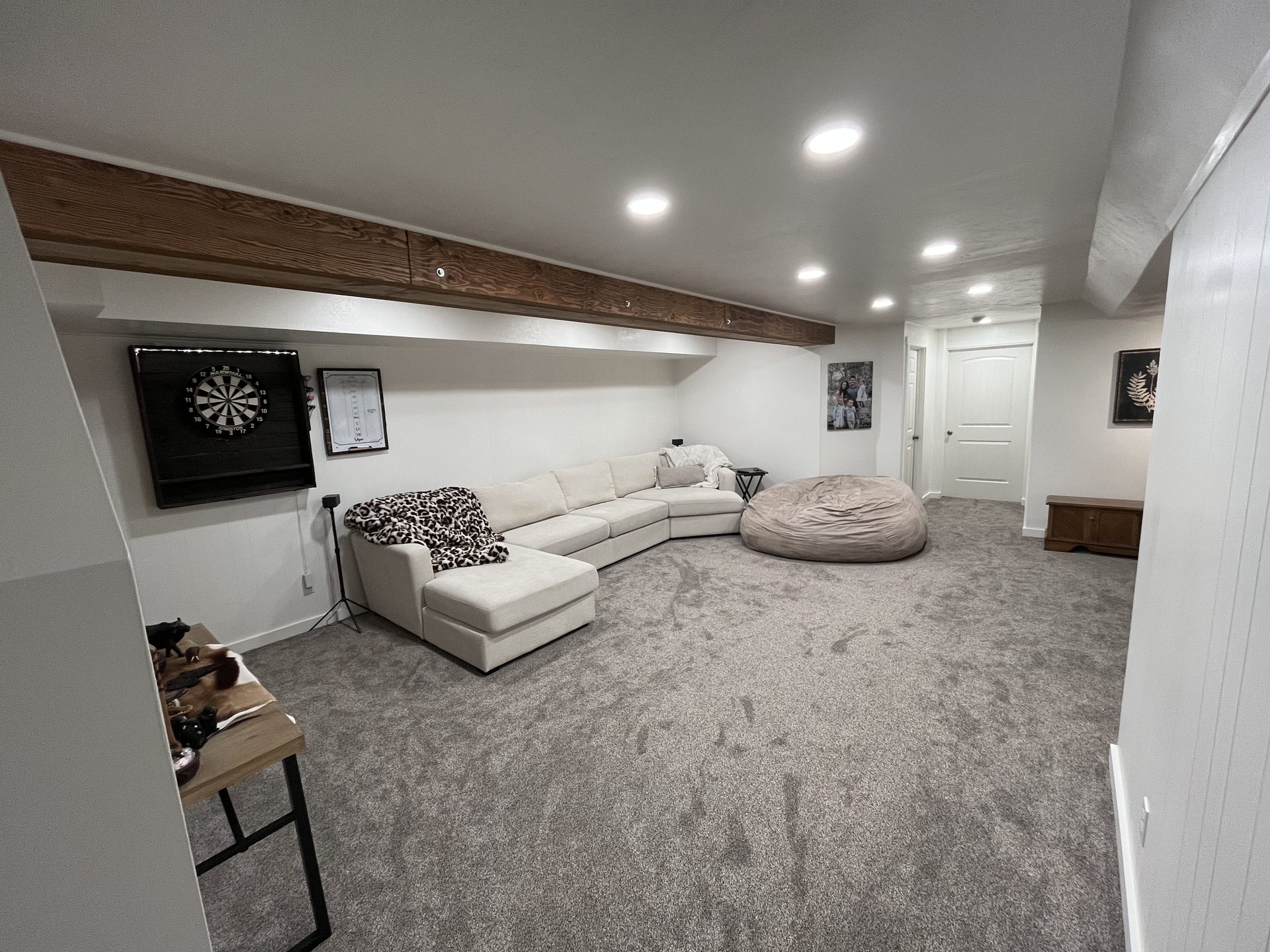 Finished basement rec room — carpet, recessed lighting, wood beam